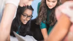 An image of a group of students looking at their books together. They seem to be involved in a discussion.